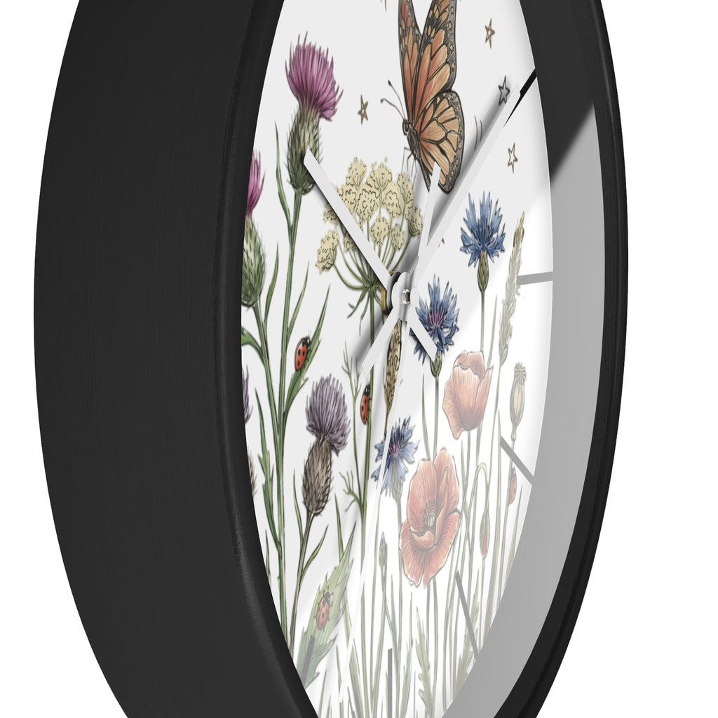 Side view of a round black wall clock with white hands and  floral and butterfly design on a white background