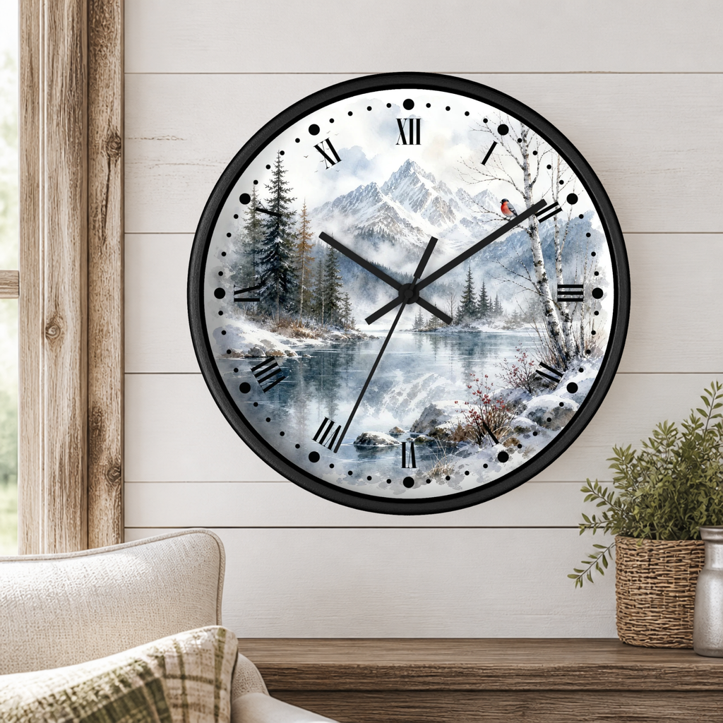 A round wall clock with a black frame and a scenic winter mountain landscape printed on the face, mounted on a white shiplap wall above a wooden table with a plant and part of a chair visible.