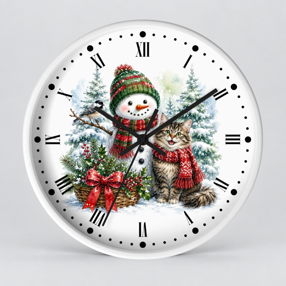 A round white wall clock featuring a festive Christmas illustration with a snowman and a tabby cat wearing red scarves, surrounded by pine trees and a basket of greenery, set against a light gray background.