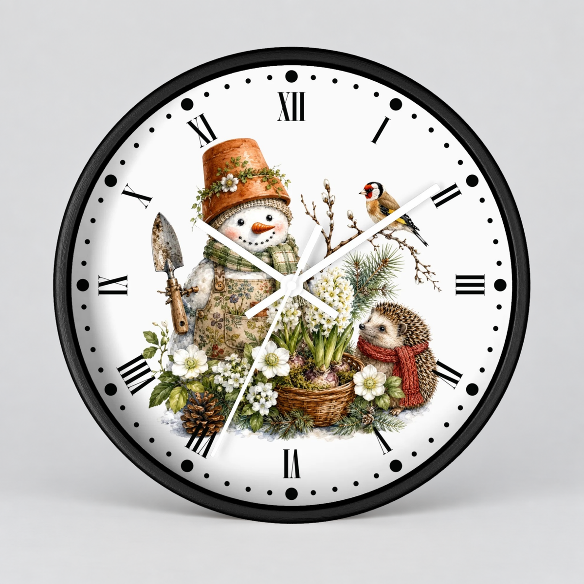 A round wall clock with a black frame and a white face featuring a winter illustration of a snowman, hedgehog, bird, flowers, and pinecones, with black Roman numerals and white hands on a light gray background.
