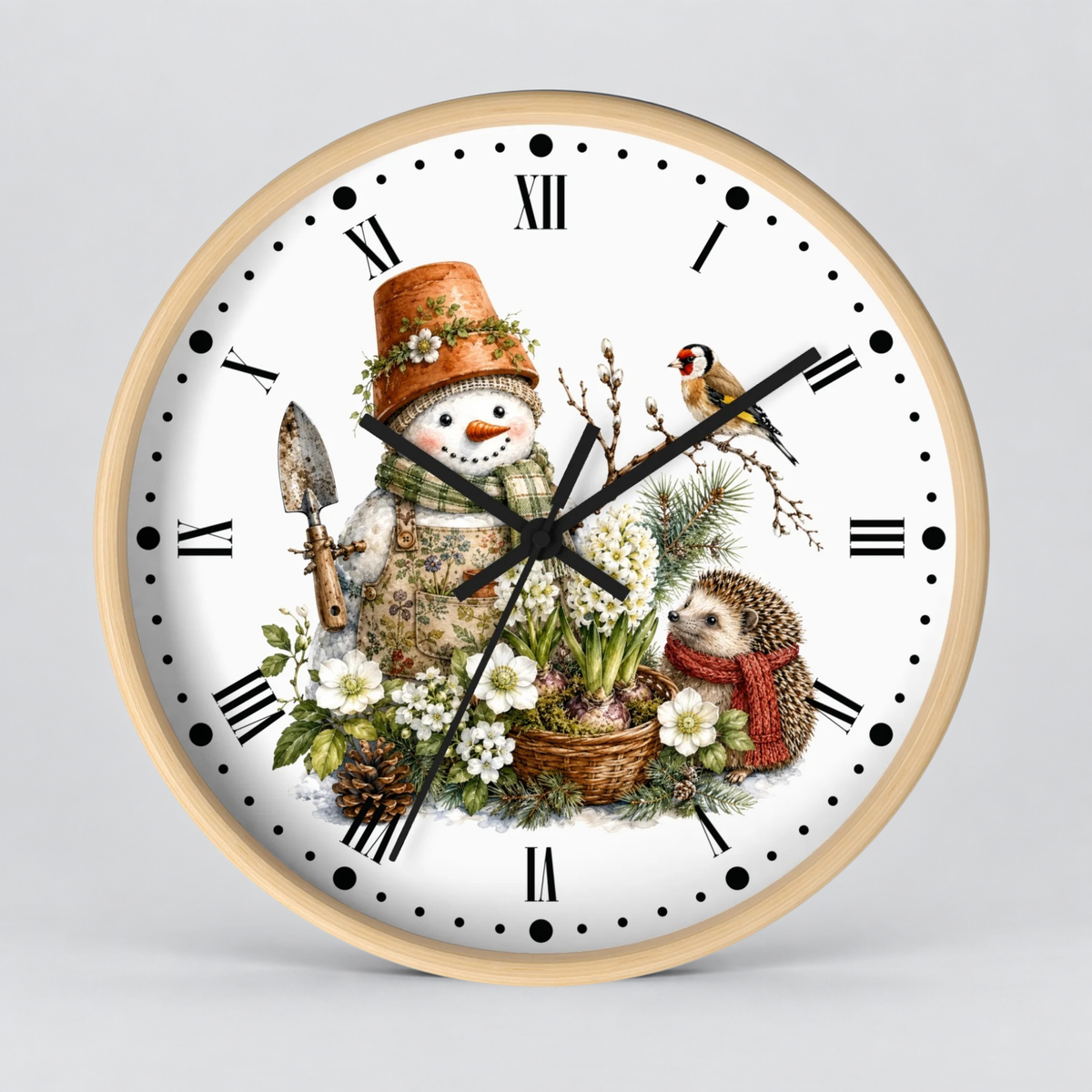 A round wall clock with a light wood frame and a white face featuring a winter garden illustration. The design includes a snowman in a terracotta pot hat, a small bird, a hedgehog in a red scarf, flowers, greenery, and black Roman numerals with black hands.