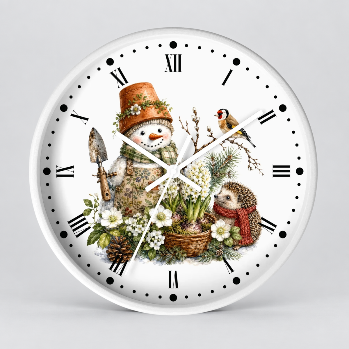 A round white wall clock with black Roman numerals and hour markers, featuring a whimsical winter garden illustration on the face. The design includes a snowman in gardening clothes with a flower pot hat, white flowers, a hedgehog in a red scarf, pinecones, and a small bird.