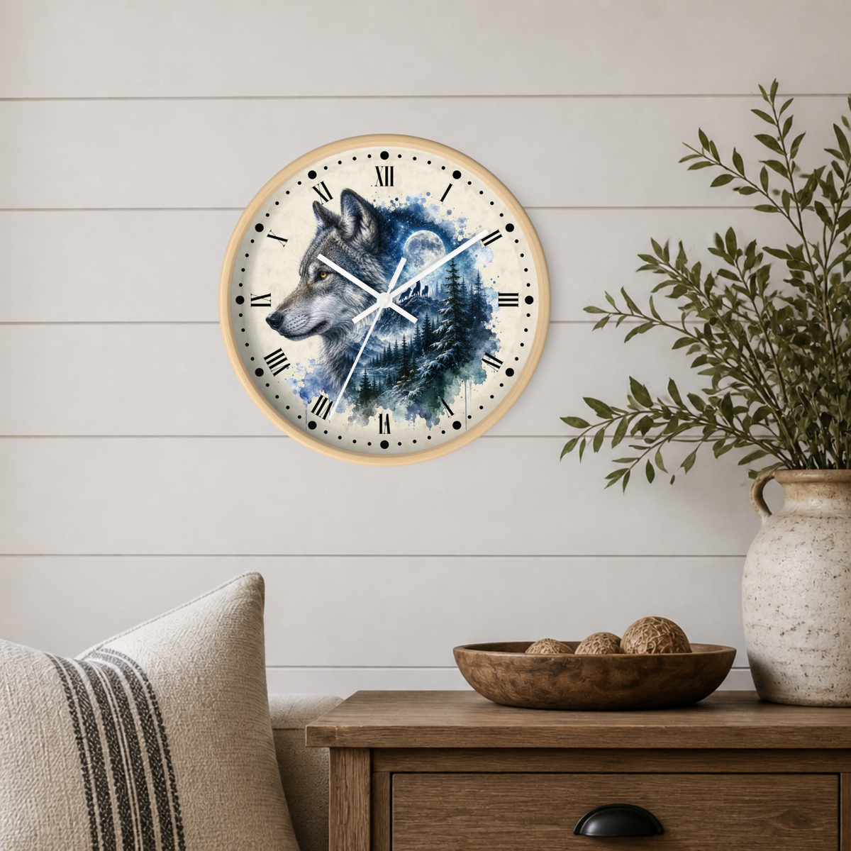 A round wall clock with a watercolor wolf illustration, mounted on a white shiplap wall above a wooden side table with a vase and bowl.