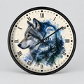 A round wall clock with a black frame and a cream-colored face featuring a painted gray wolf over a blue watercolor forest and full moon.
