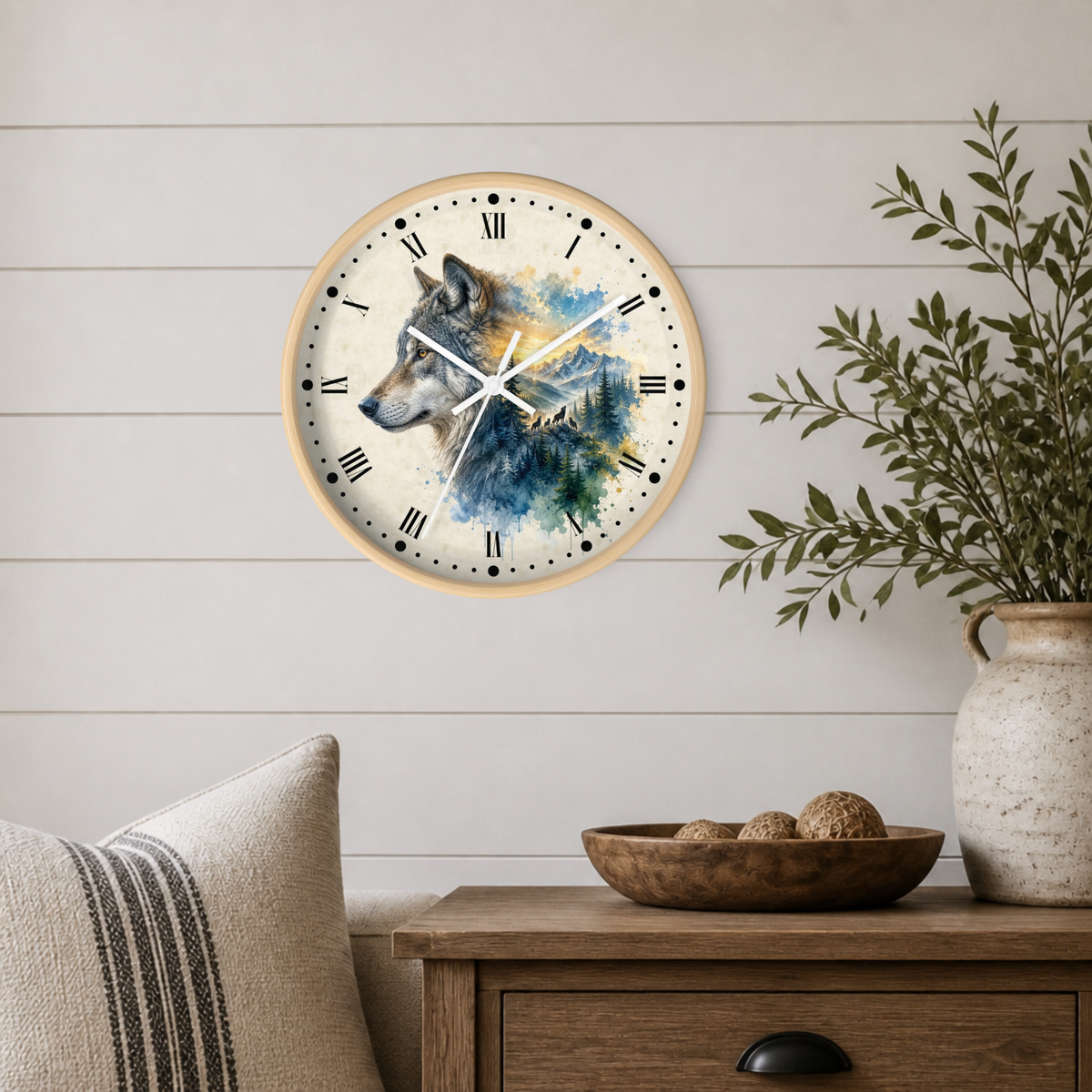 Round wall clock with a wolf illustration in blue, gray, and cream tones, mounted on a white shiplap wall above a wooden side table with a vase and bowl.