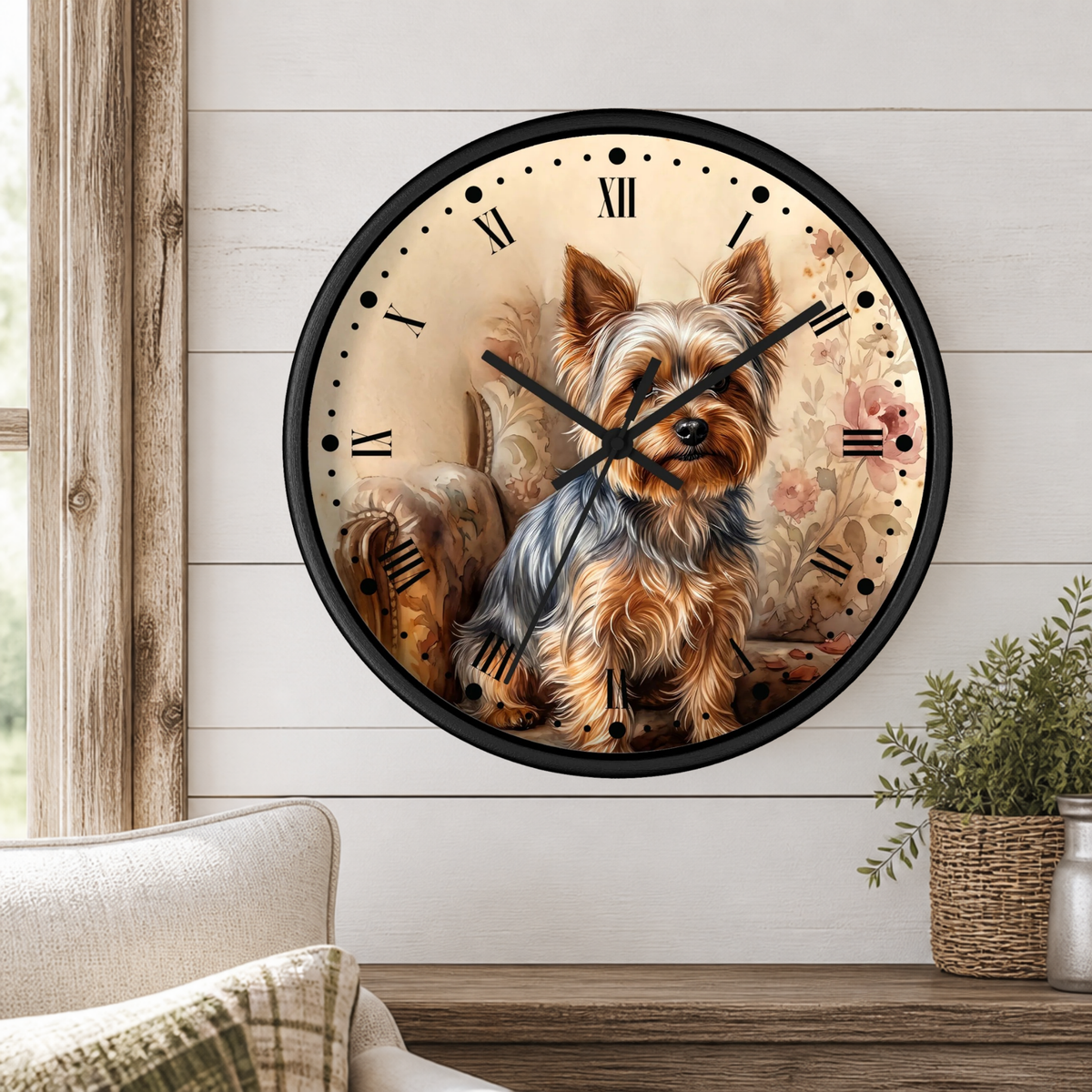 A round wall clock with a black frame and a printed illustration of a Yorkshire Terrier dog on the face, mounted on a white wood-paneled wall above a wooden shelf with a small potted plant.
