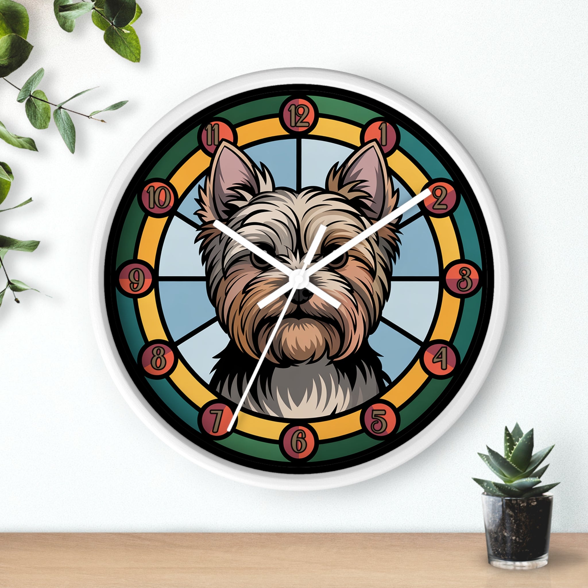 Round white wall clock with white hands and a yorkie dog's face design on a white wall with plants.