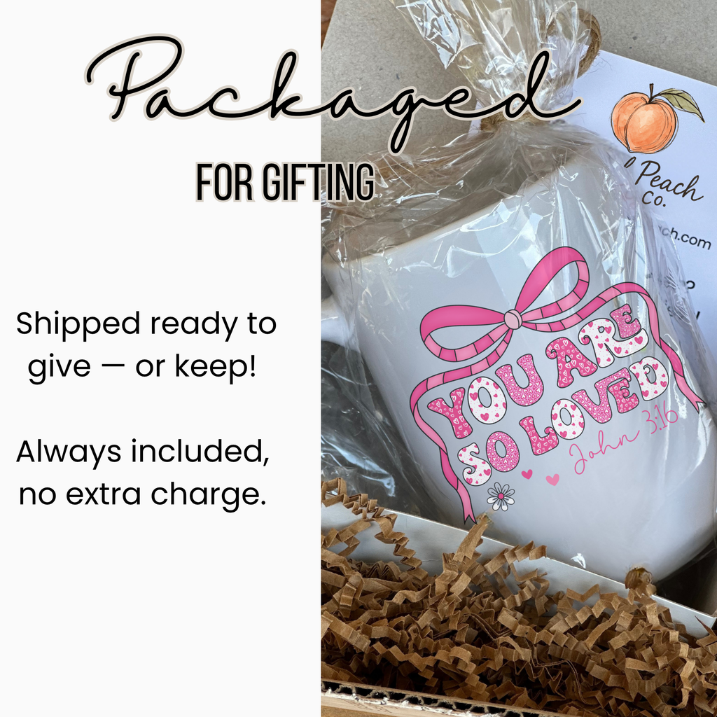 White mug with pink text and design, wrapped in clear plastic with brown paper, labeled 'Peach Co'.