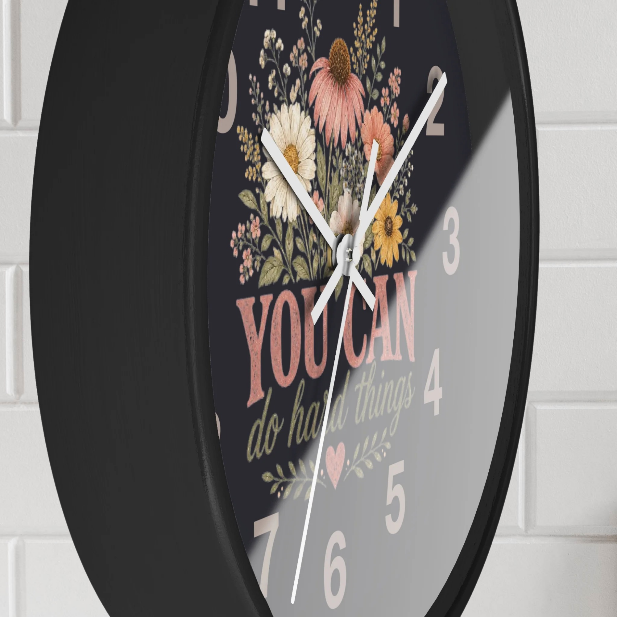 Wall clock with floral design and motivational quote on a white brick wall background