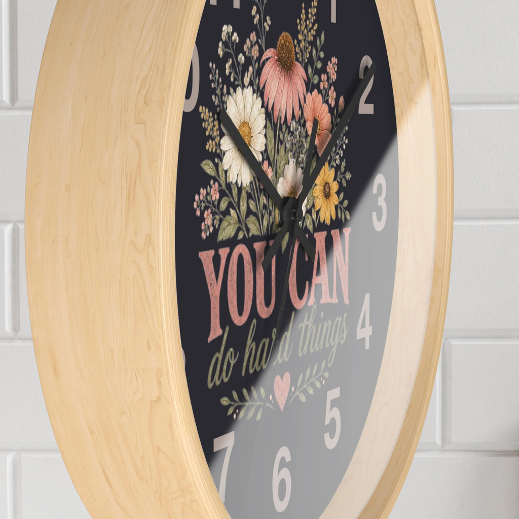 Decorative wall clock with floral design and motivational quote on a light wooden frame.