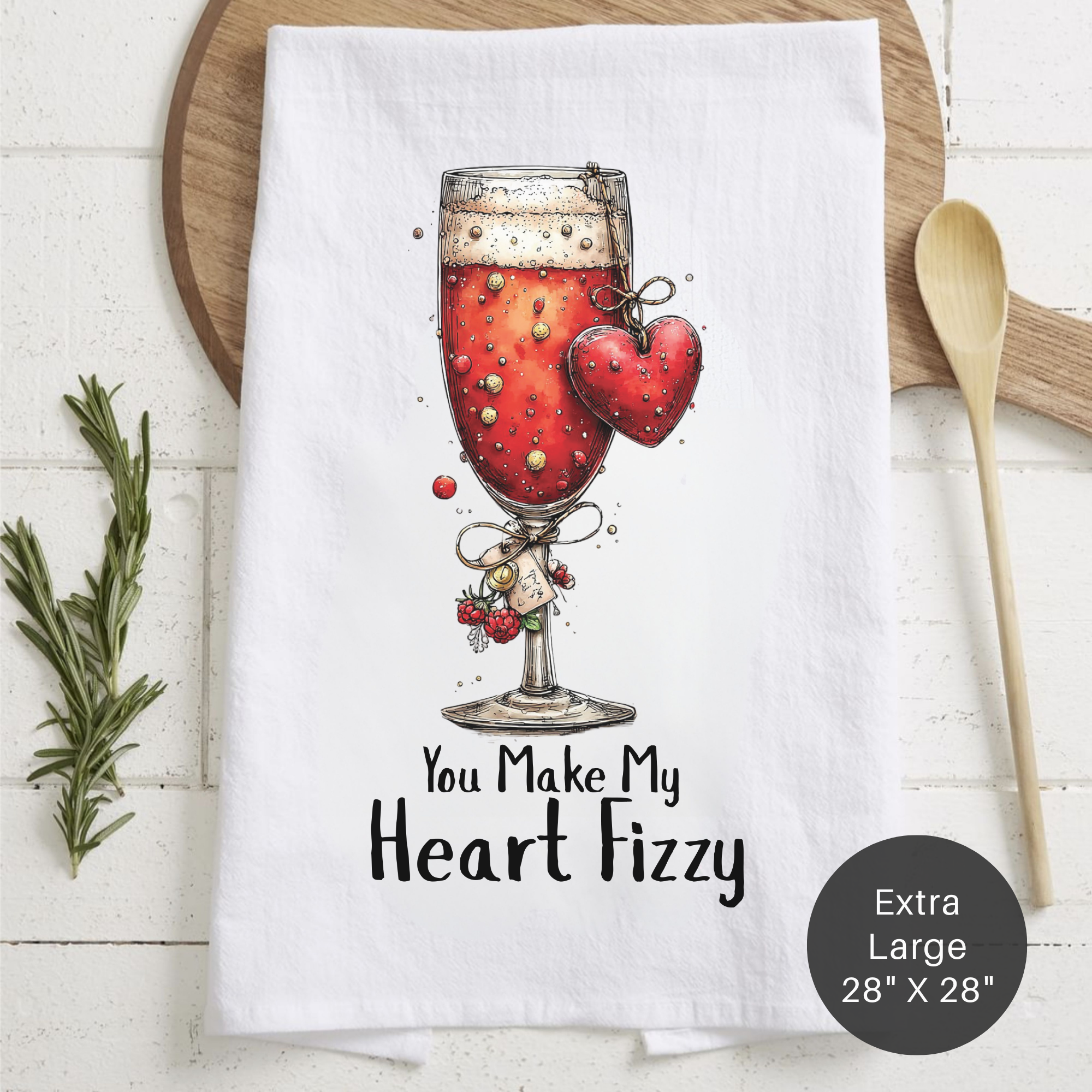 Tea towel with a glass of champagne and heart design, text 'You Make My Heart Fizzy', on a wooden board.