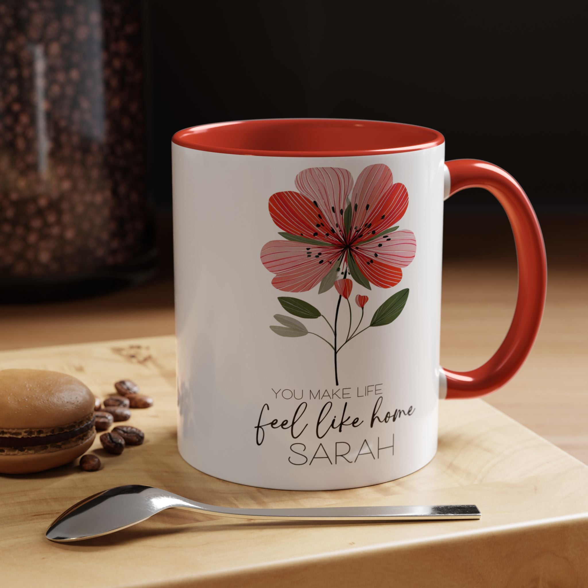 11oz. White mug with red interior and handle, featuring a floral design and text, on a wooden surface with coffee beans and a spoon.