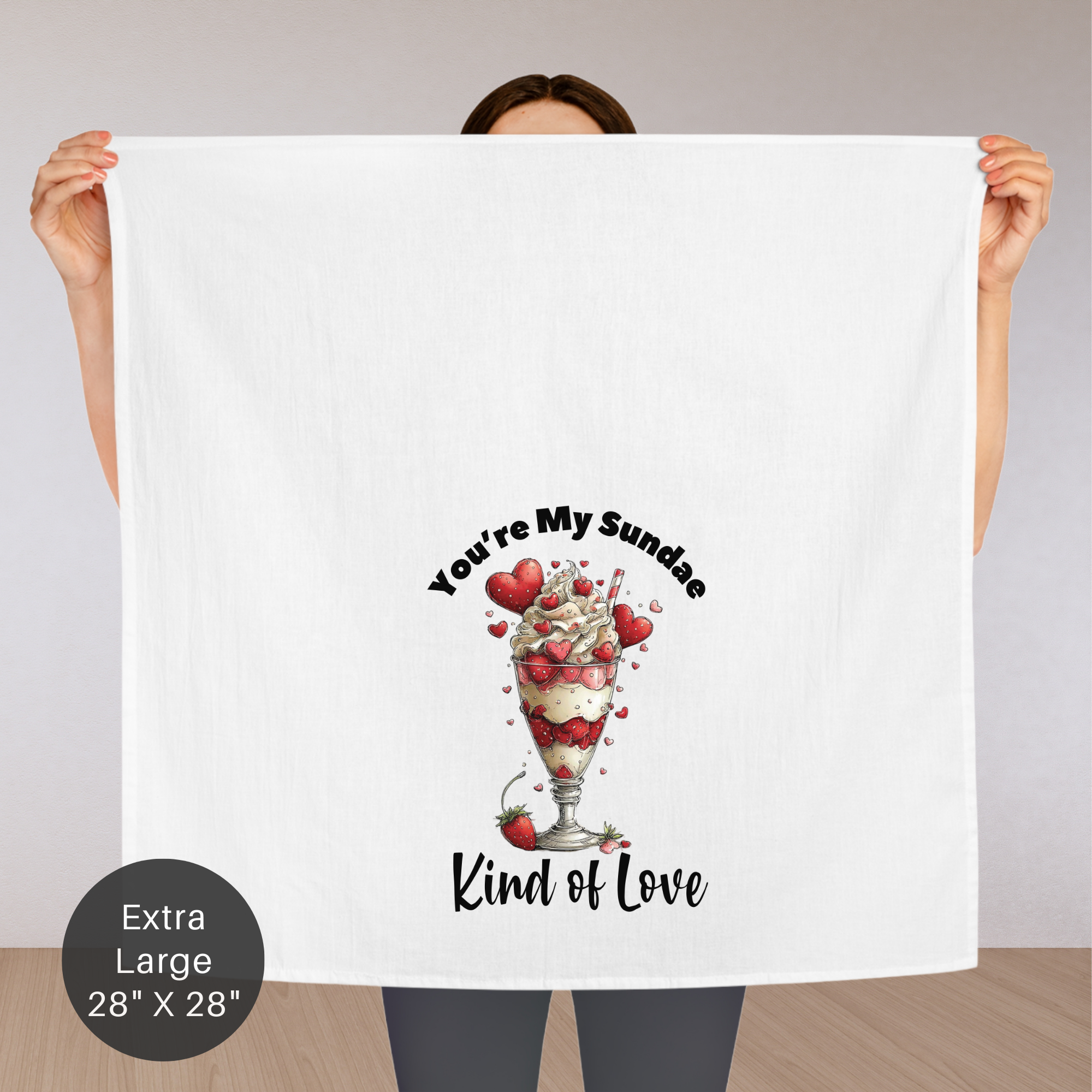Person holding an extra large tea towel with a dessert illustration and text 'You're My Sundae Kind of Love'.