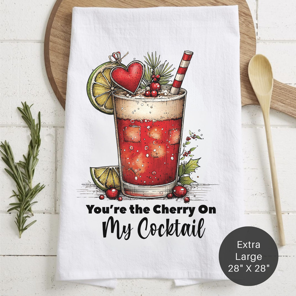Tea towel with cocktail illustration and text ' You're the Cherry On My Cocktail' on a wooden surface