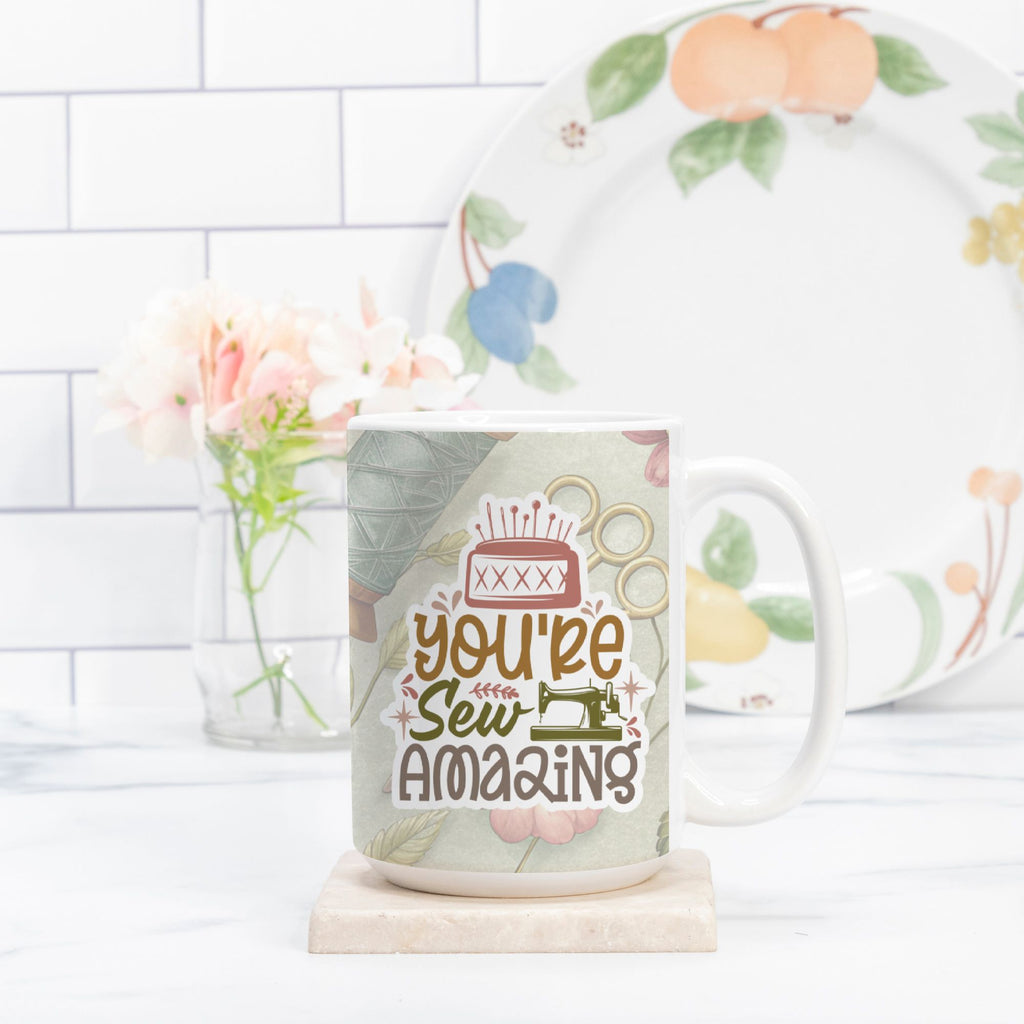 Mug with 'You're Sew Amazing' design and floral-patterned plate in the background