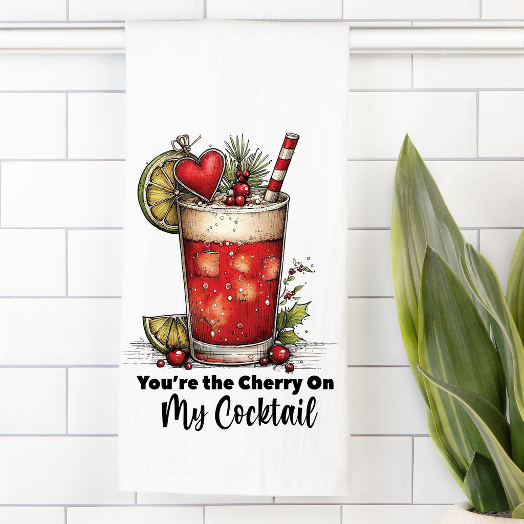 Decorative kitchen towel with a cocktail illustration and text on a white tiled wall.