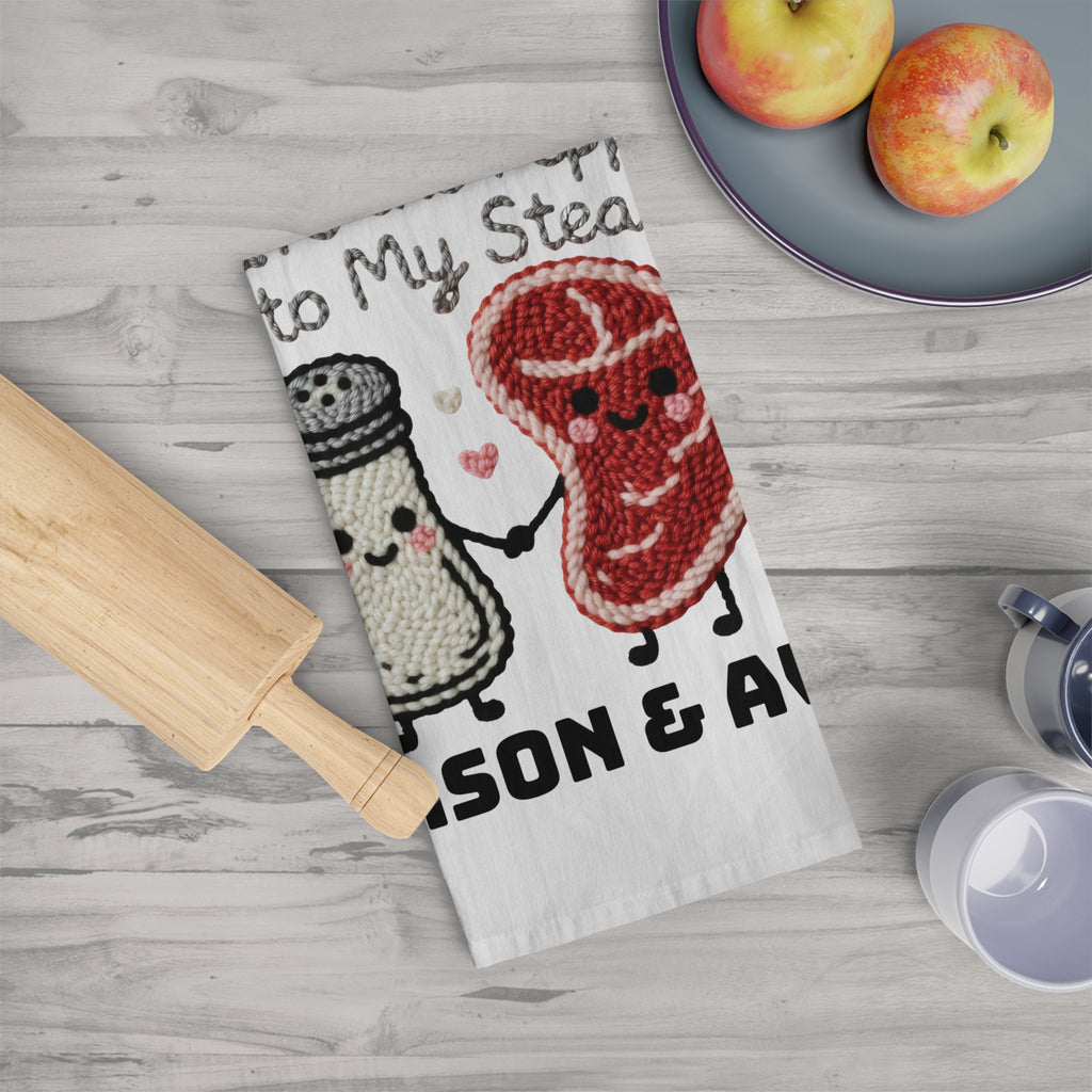 Kawaii-style steak and pepper shaker design on a kitchen towel with a wooden rolling pin and apples in the background.