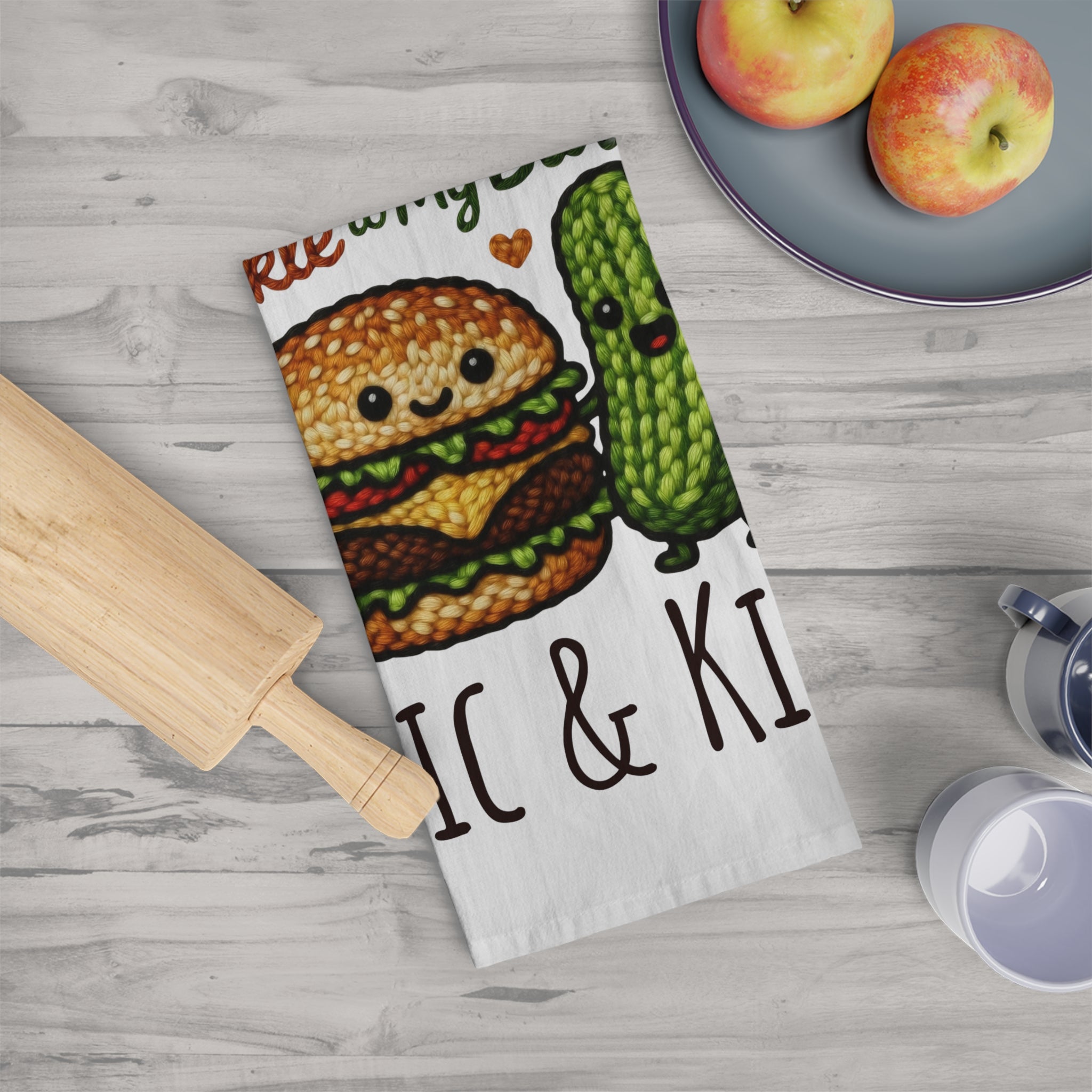 Kitchen towel with cartoon character design on a wooden surface with apples and a rolling pin.