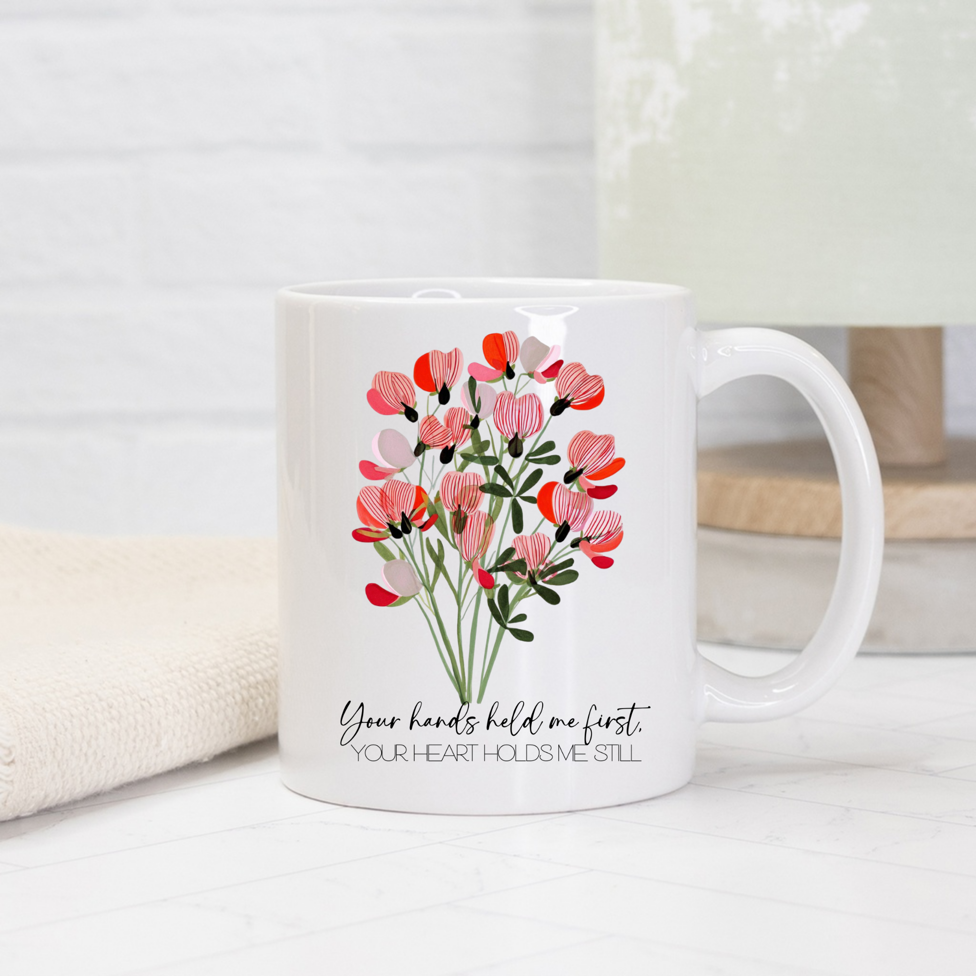 11oz white mug with floral design and text 'Your hands held me first, Your Heart Holds Me Still' on a light background