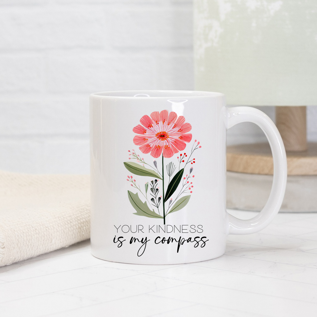 White 11oz mug with a pink flower design and text 'Your kindness is my compass' on a light background.