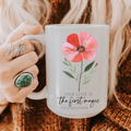 Person holding a 15oz mug with a floral design and text on a textured surface