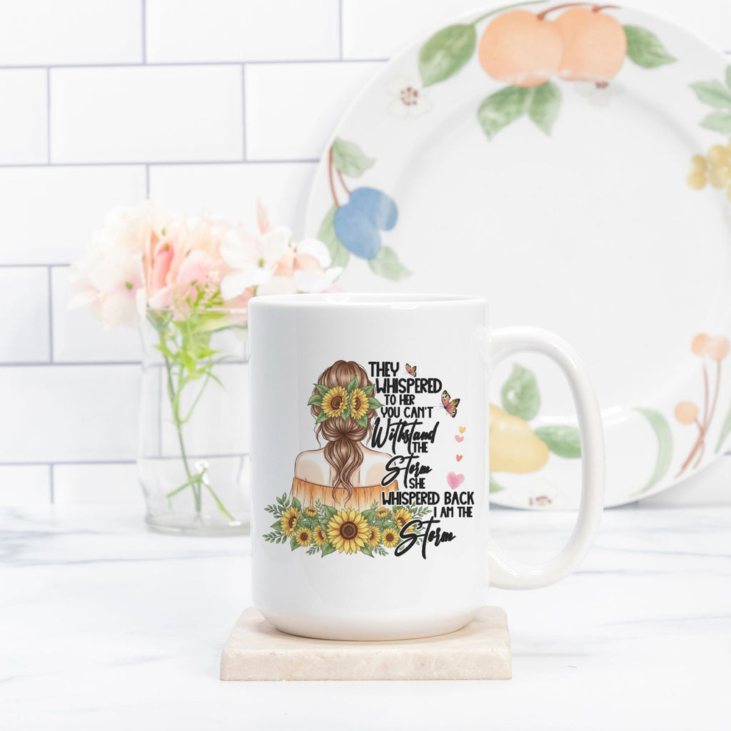 White mug with floral design and text on a white surface with a decorative plate in the background.