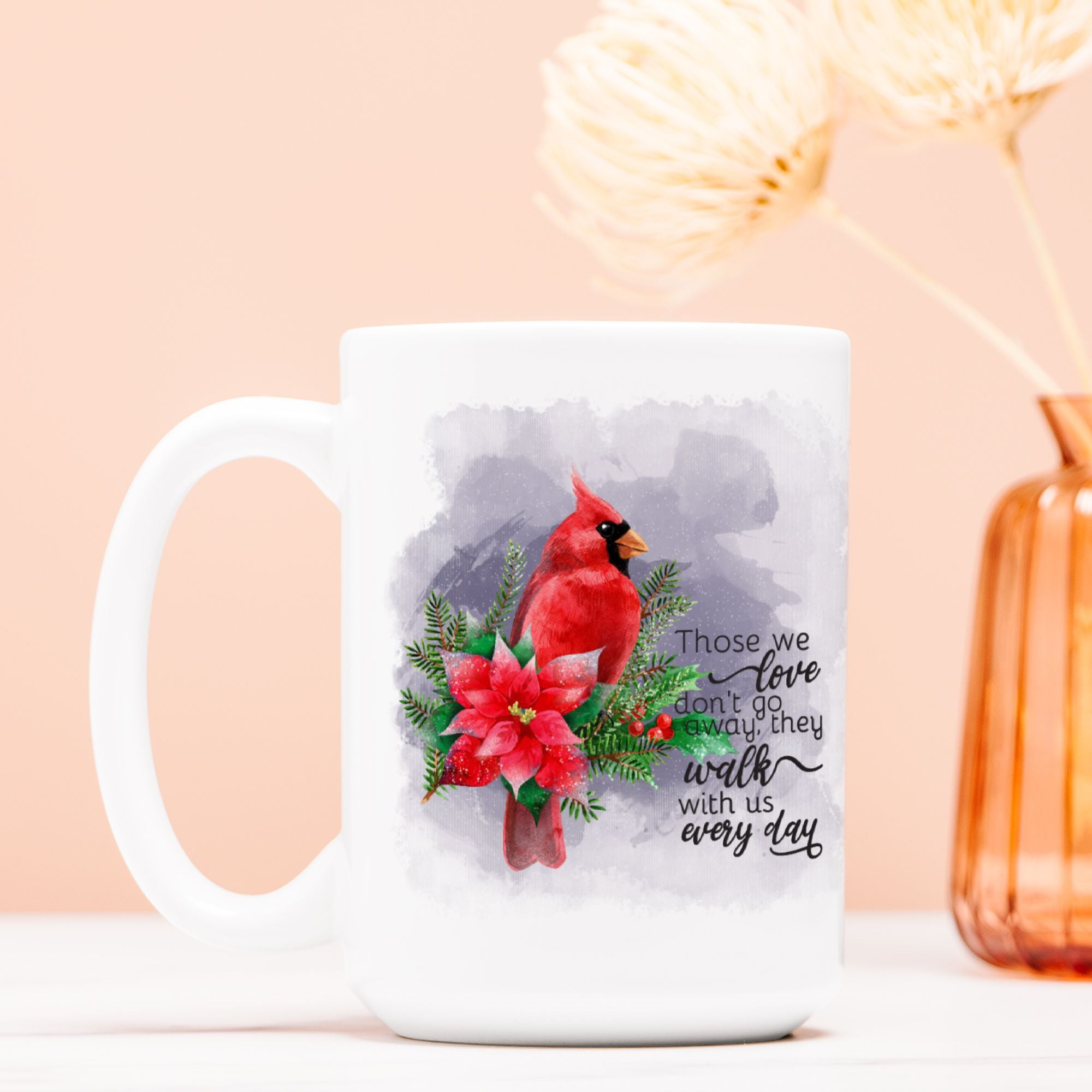 White mug with a red cardinal and poinsettia design on a light pink background