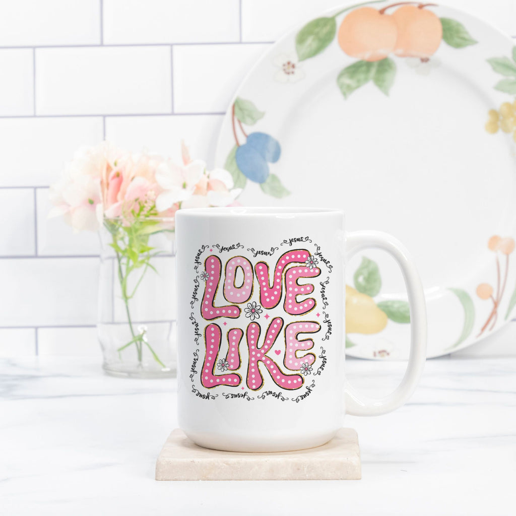 Mug with 'LOVE LIKE' text on a kitchen counter with a decorative plate in the background.