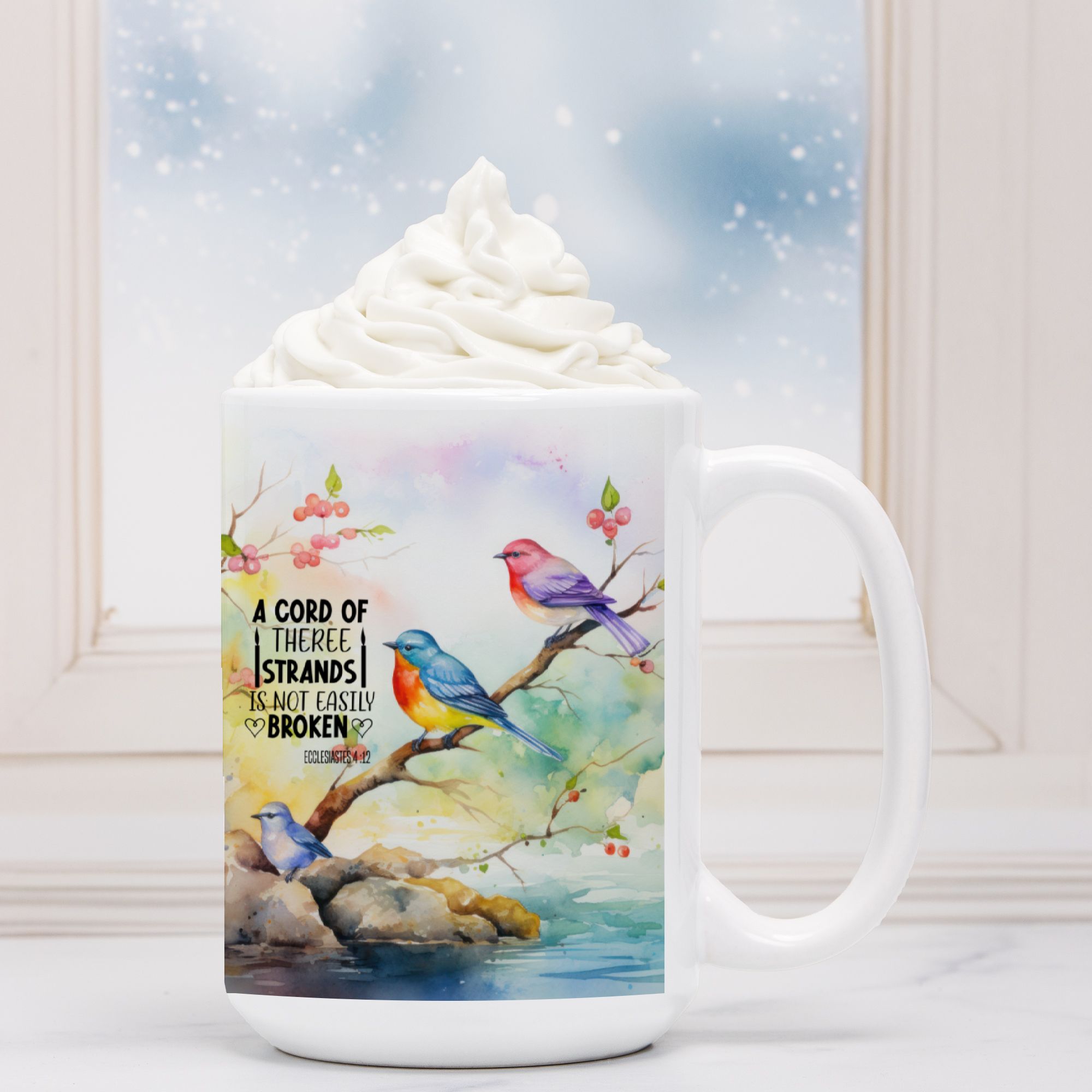 White mug with colorful birds design and text, filled with hot chocolate and whipped cream.