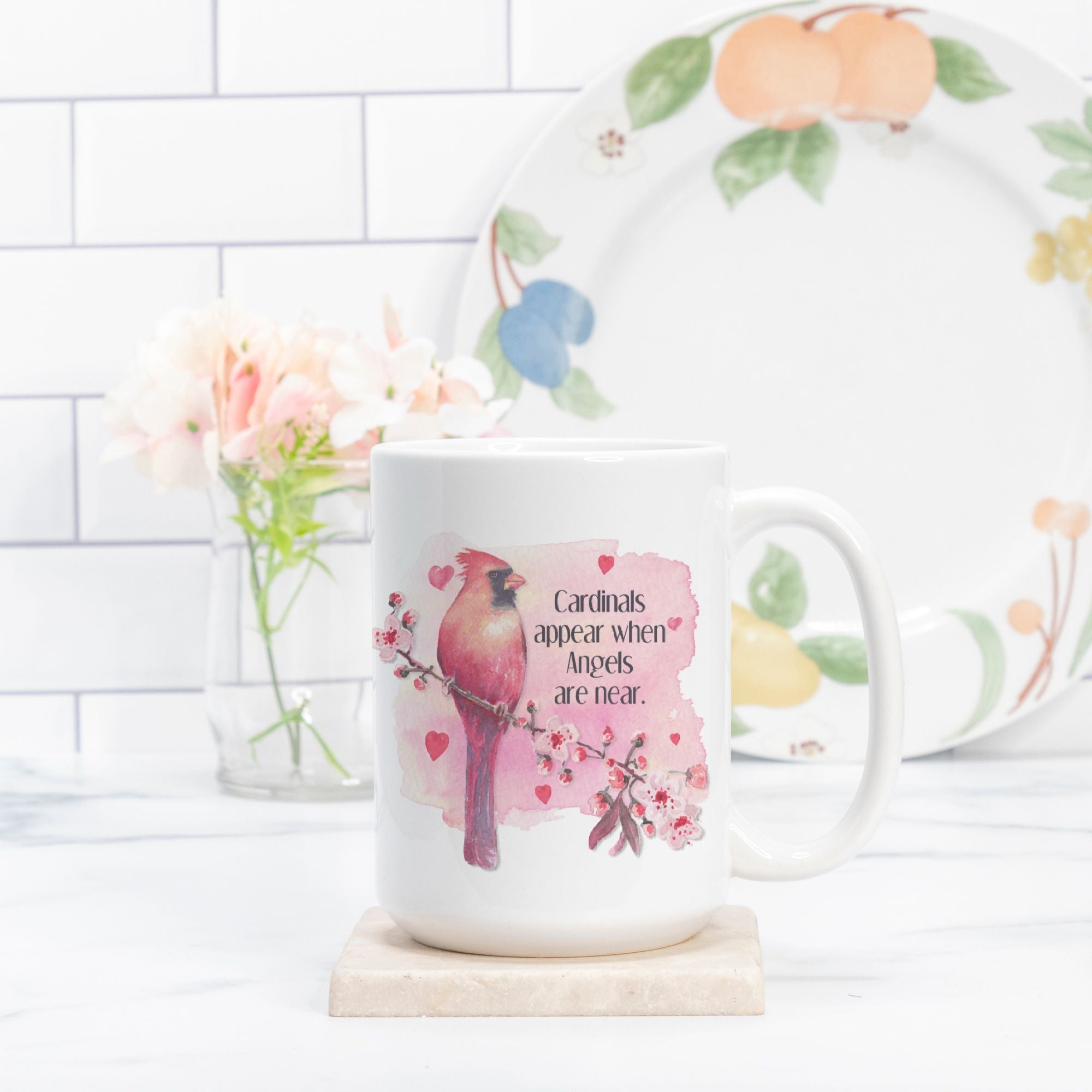 White mug with a bird design and text, placed on a white surface with a decorative plate in the background.