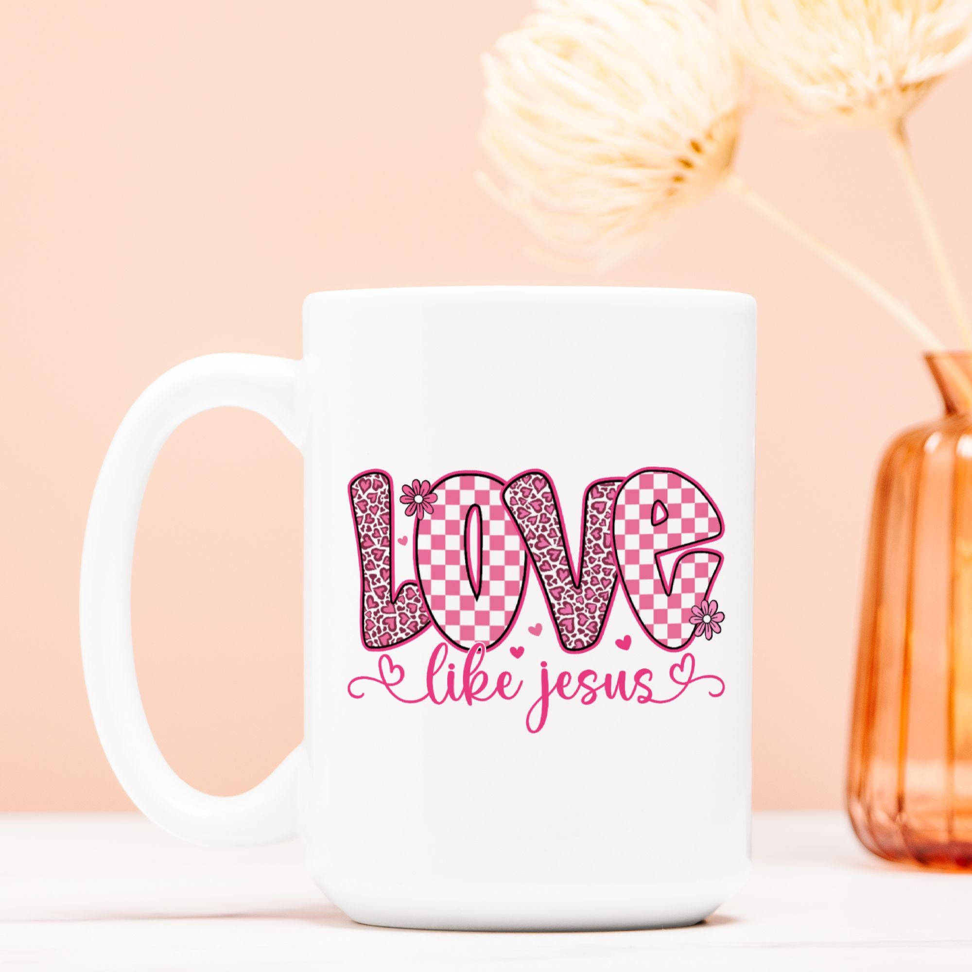 White mug with pink 'Love like Jesus' design on a light pink background